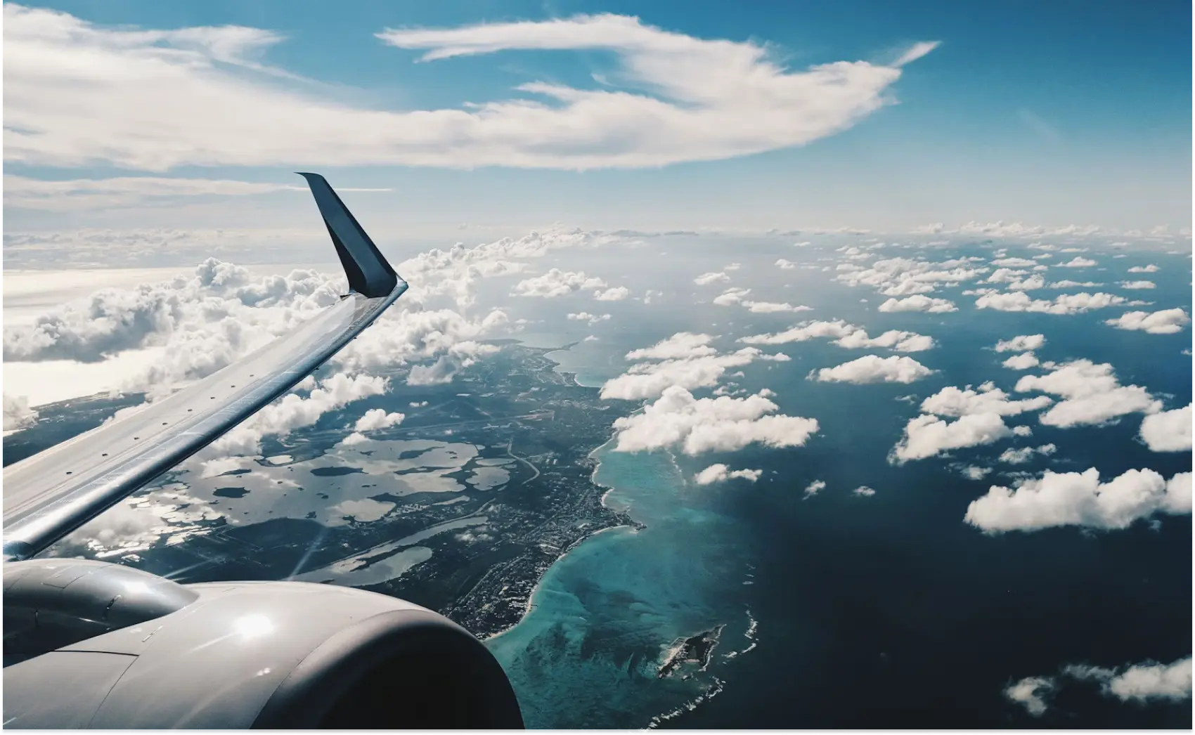 Airplane window view revealing a vast ocean and scattered clouds in the sky